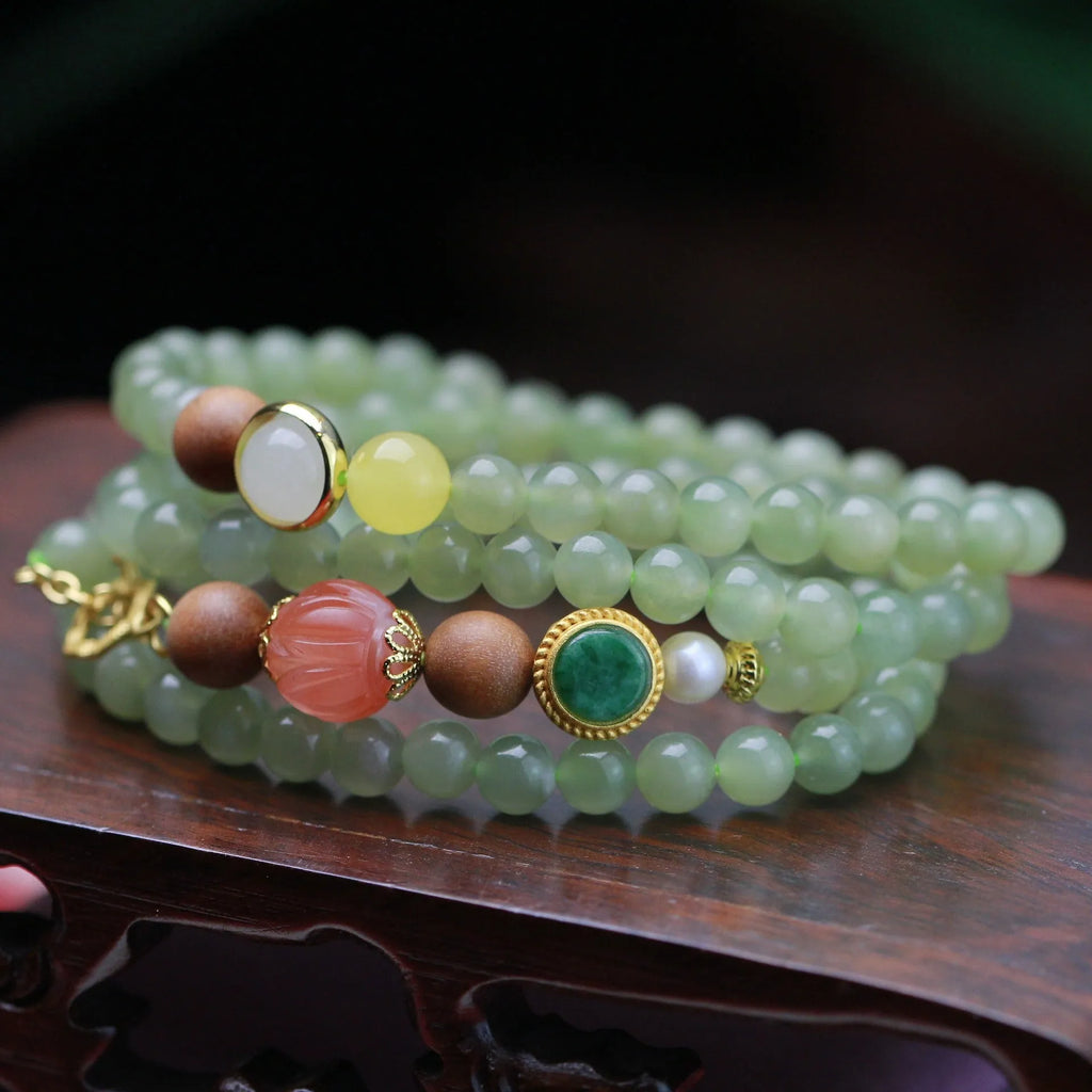 Handmade Hetian jade and white sandalwood necklace with red lotus beads and fu charm, shown with matching bracelet.