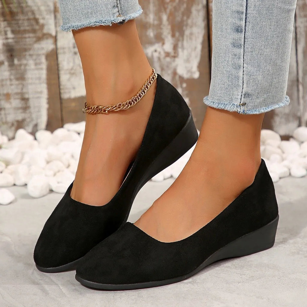 Women's plus size pointed toe wedge pumps in suede with a shallow cut and low rubber heel.