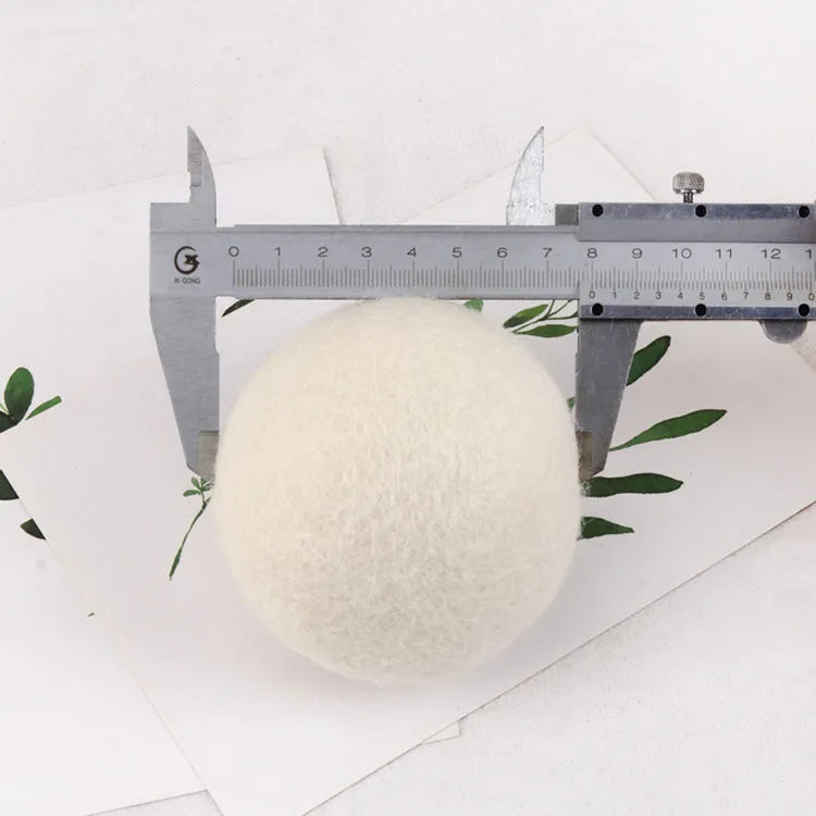 Set of 100% wool felt laundry drying balls in various sizes next to a plain cotton storage bag.