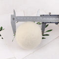 Set of 100% wool felt laundry drying balls in various sizes next to a plain cotton storage bag.