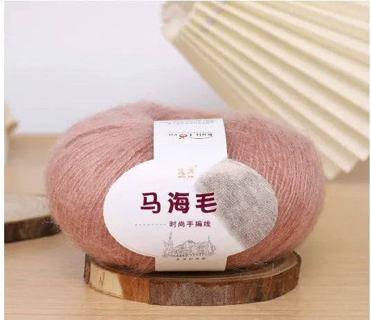 A ball of mohair yarn in a selected colour next to a hand-woven scarf example, showcasing the DIY kit.