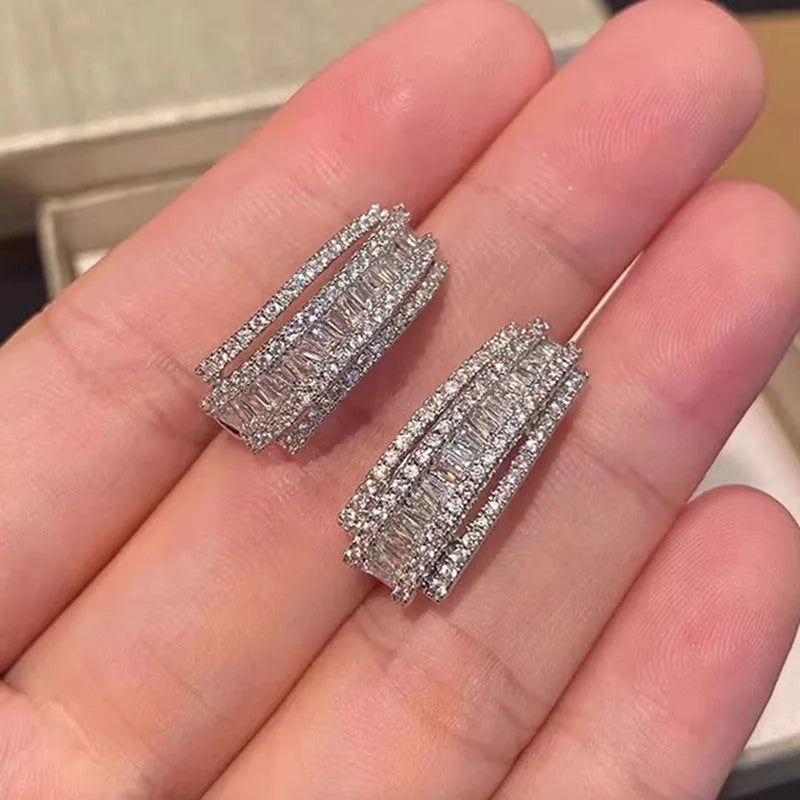 A pair of women's geometric stud earrings in white gold colour with a central inlaid zircon stone.