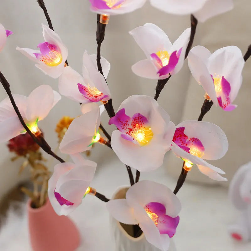 Pink fabric-covered LED Phalaenopsis orchid branch light, 65cm long, with warm white bulbs illuminated on a dark surface.