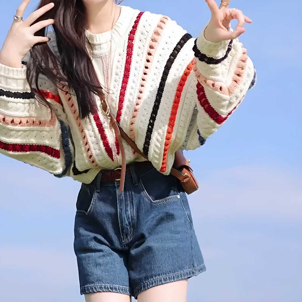 Retro rainbow striped pullover sweater with batwing sleeves on a hanger.