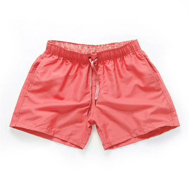 Men's polyester surf shorts in multiple colours on a beach background, showing straight leg design.