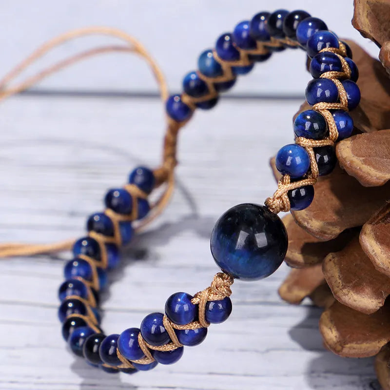 Close-up of a handmade woven bracelet featuring blue tigereye beads in a geometric pattern on a wrist.