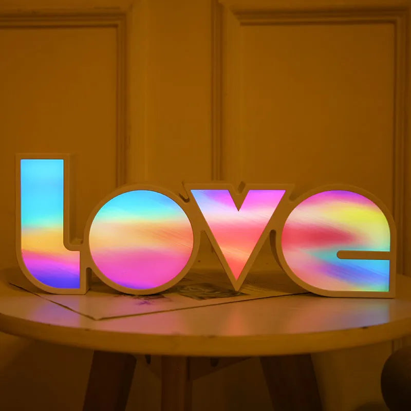 LED LOVE light with rainbow-coloured plastic lampshade on a desk