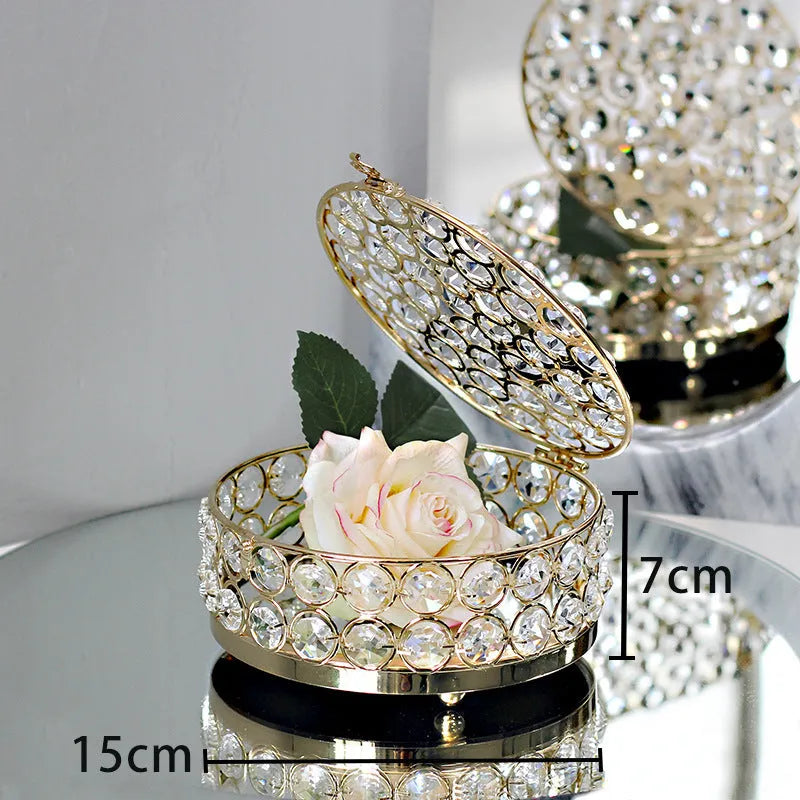 Crystal clear glass jewelry box with French gold metal frame on a table.