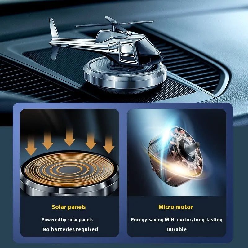 Silver metal solar helicopter car perfume ornament with rotating blades on a dashboard.