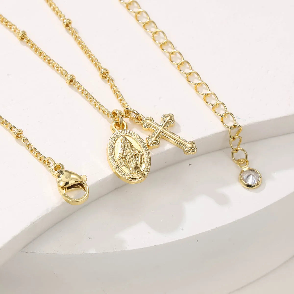 Gold geometric cross necklace with Virgin Mary detail on a 60cm chain, pendant is 3cm tall.