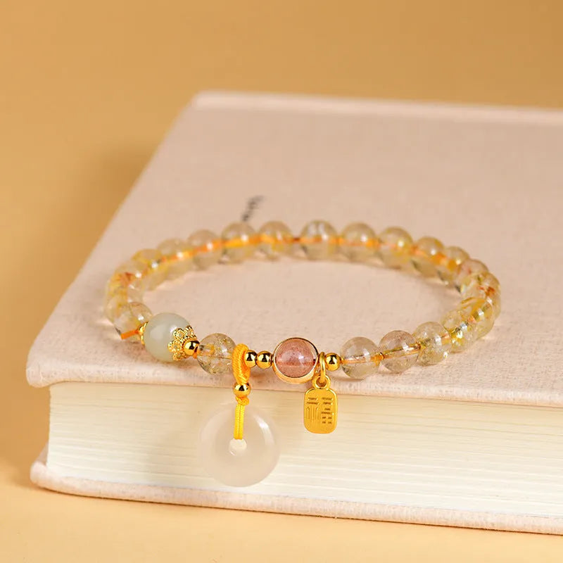Gold rutilated quartz bracelet with safety buckle and geometric blessing card pendant.