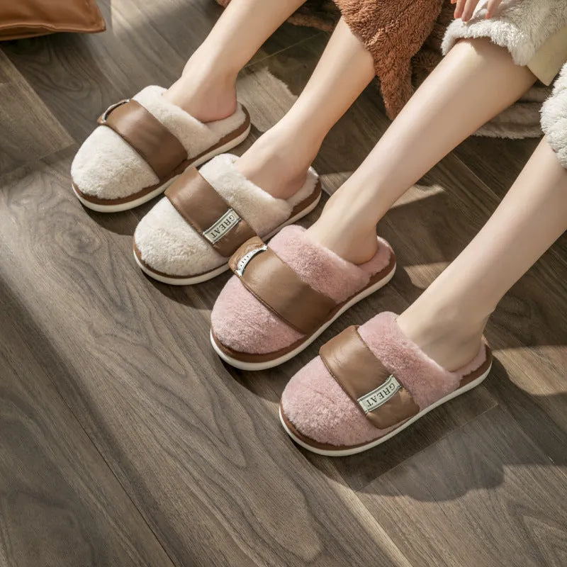 Beige women's plush slippers with a Velcro strap and non-slip plastic sole on a wooden floor.
