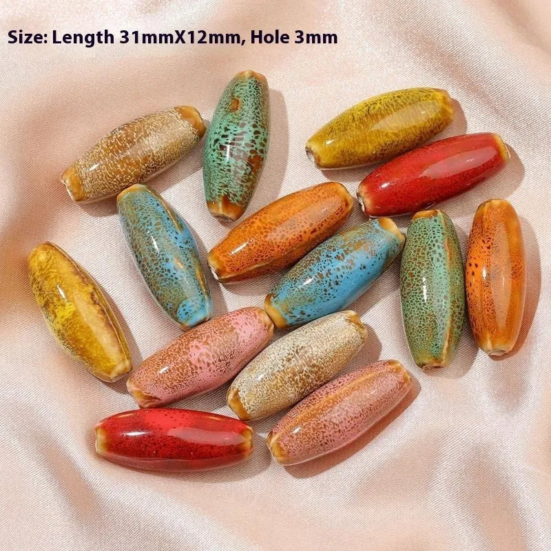 Assortment of ceramic bullet beads in pink, yellow, blue, red, coffee, green, orange, and mixed flower glaze colours.