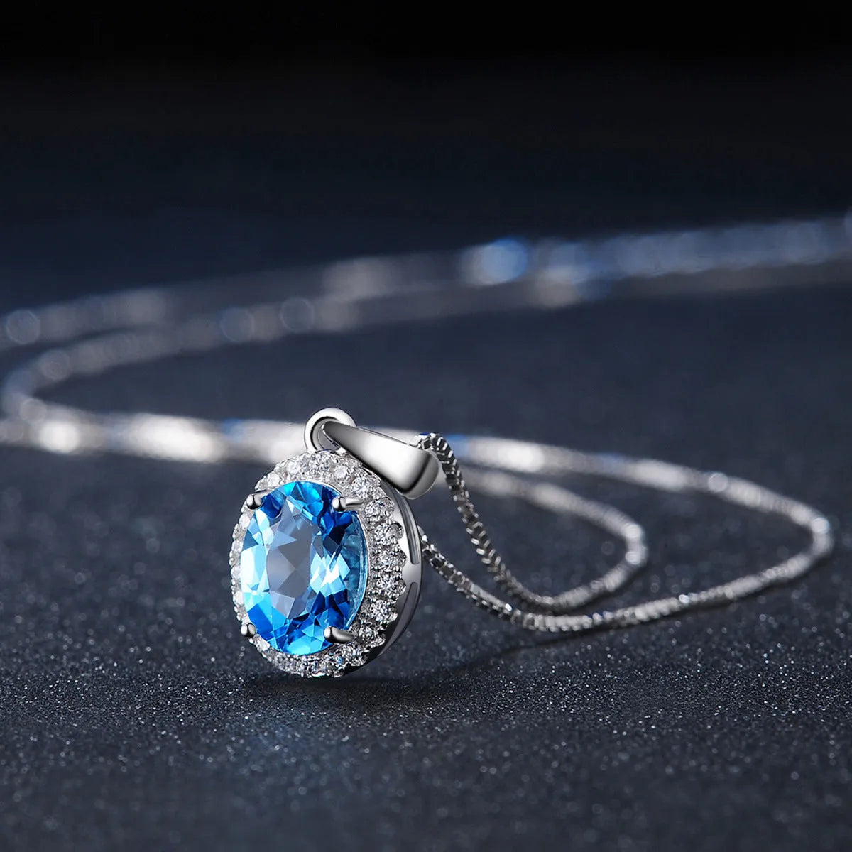 Women's four-piece sterling silver jewellery set with blue topaz gems, showing geometric earrings, ring, pendant and necklace.