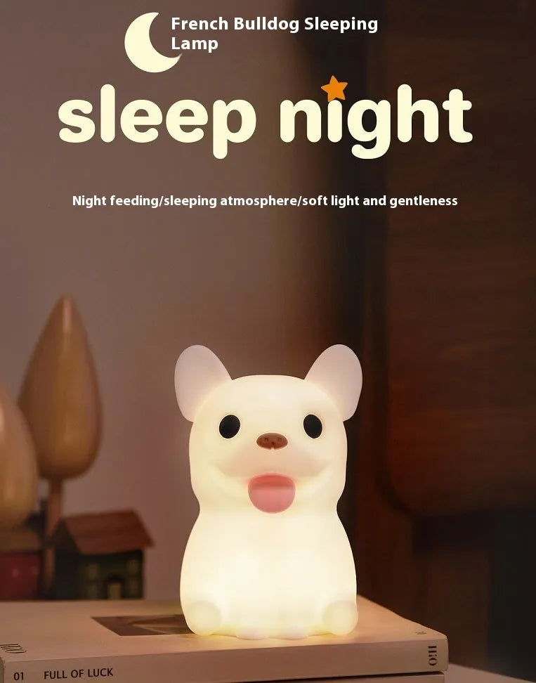 Soft silicone animal or cartoon-themed USB night light with dimming function on a bedside table.