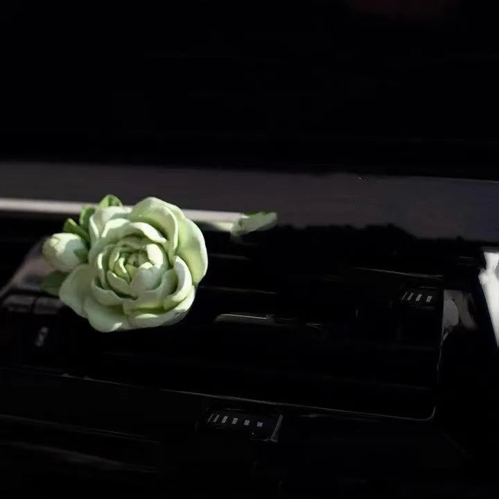 Solid jasmine car perfume diffuser clipped onto a car air vent, showing off white colour.