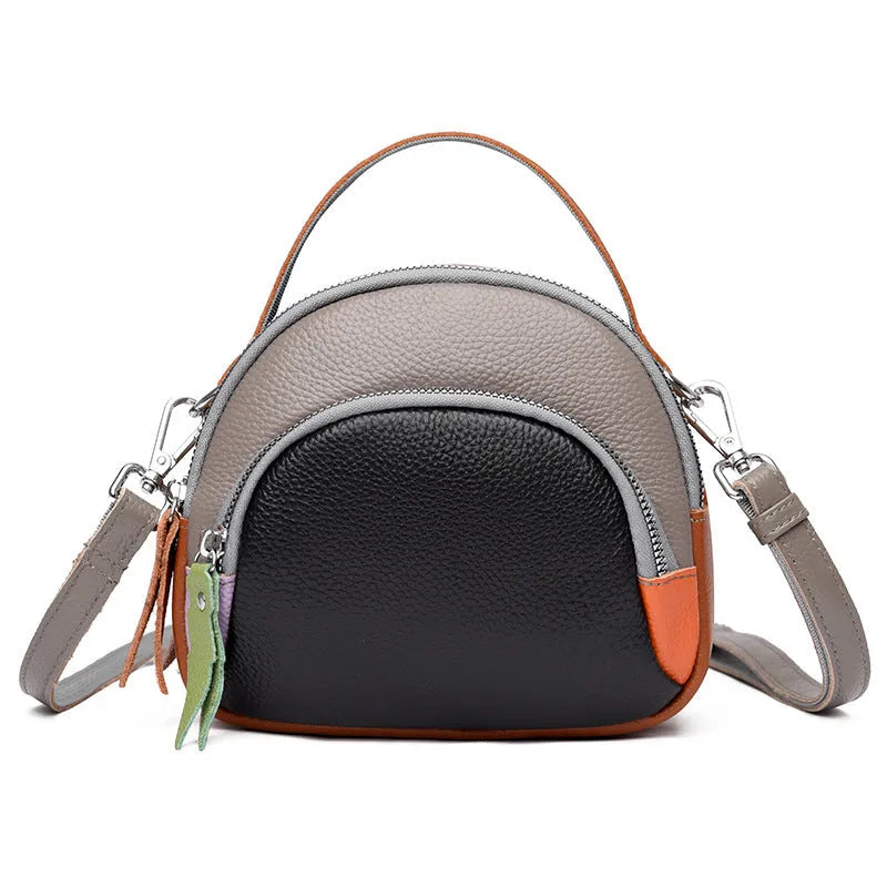 Round hand-held crossbody bag made from first layer cowhide leather with visible sewing line detail on exterior