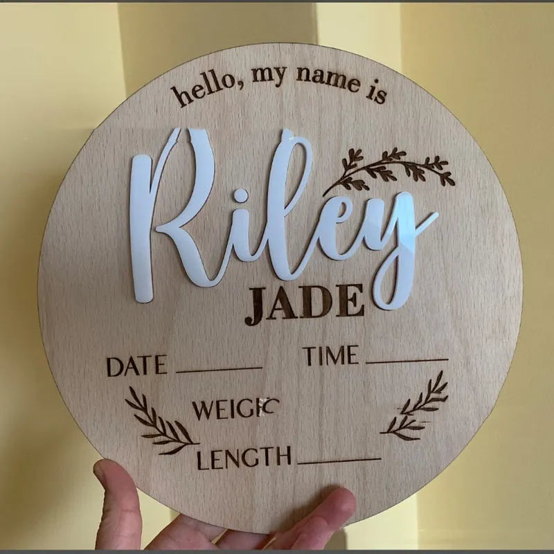 Personalised square wooden baby name plaque showing engraved birth details, in a rustic style, against a nursery background.