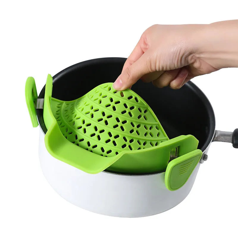 Green silicone pot drain stopper with stainless steel insert on a kitchen countertop.
