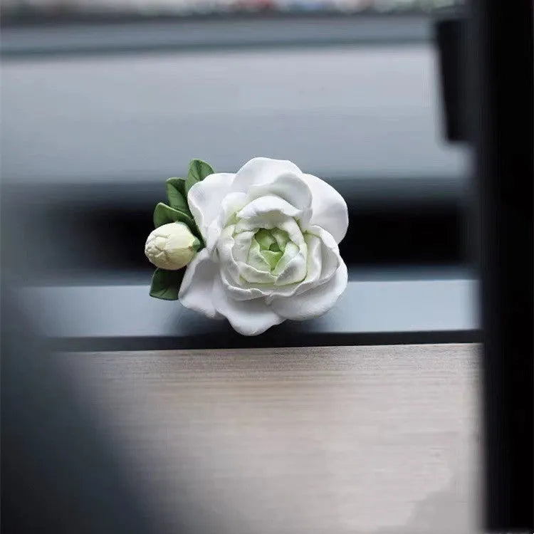 Solid jasmine car perfume diffuser clipped onto a car air vent, showing off white colour.
