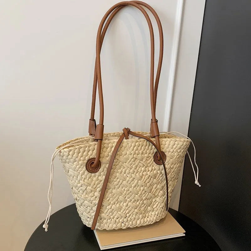 Beige woven shoulder bag with retro styling and dual-carry handles shown in horizontal square suitcase shape