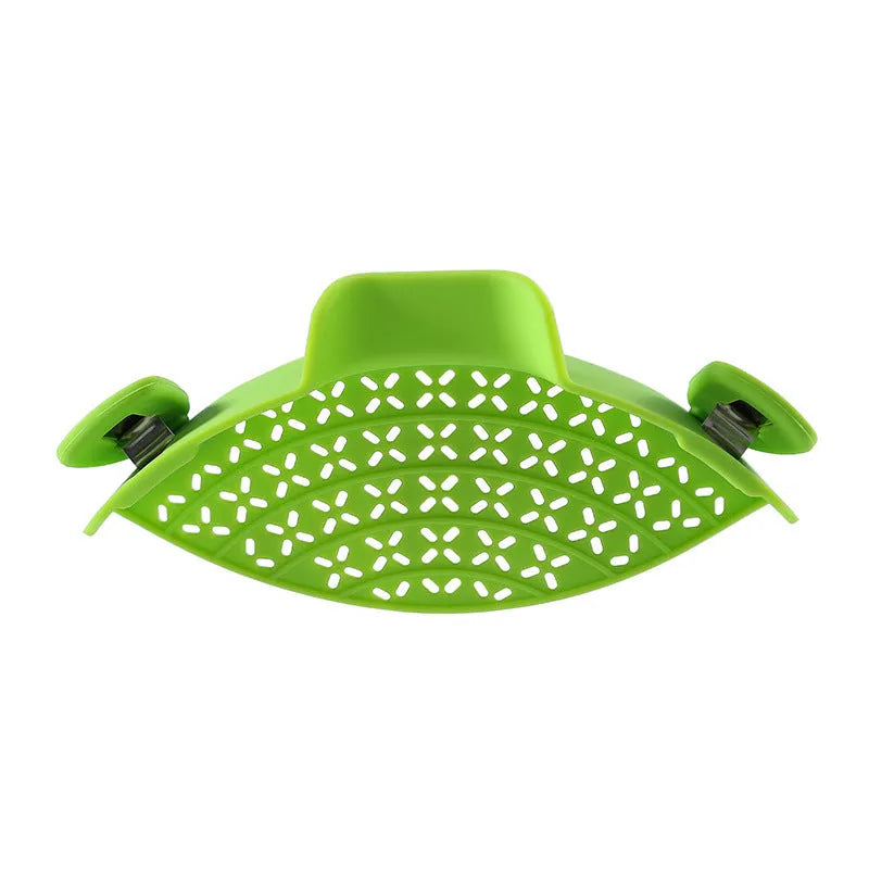 Green silicone pot drain stopper with stainless steel insert on a kitchen countertop.