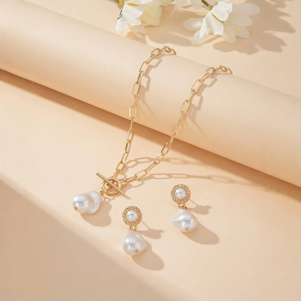 Gold-coloured retro baroque pearl necklace and matching ear studs set on a display.