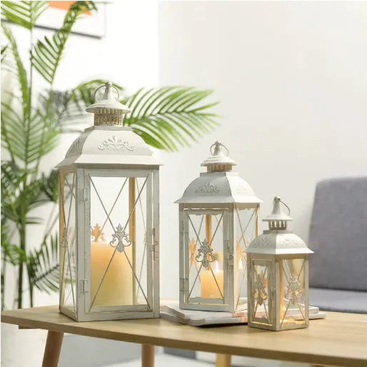 Black and white wrought iron floor-standing storm lantern with tempered glass panels in three sizes.
