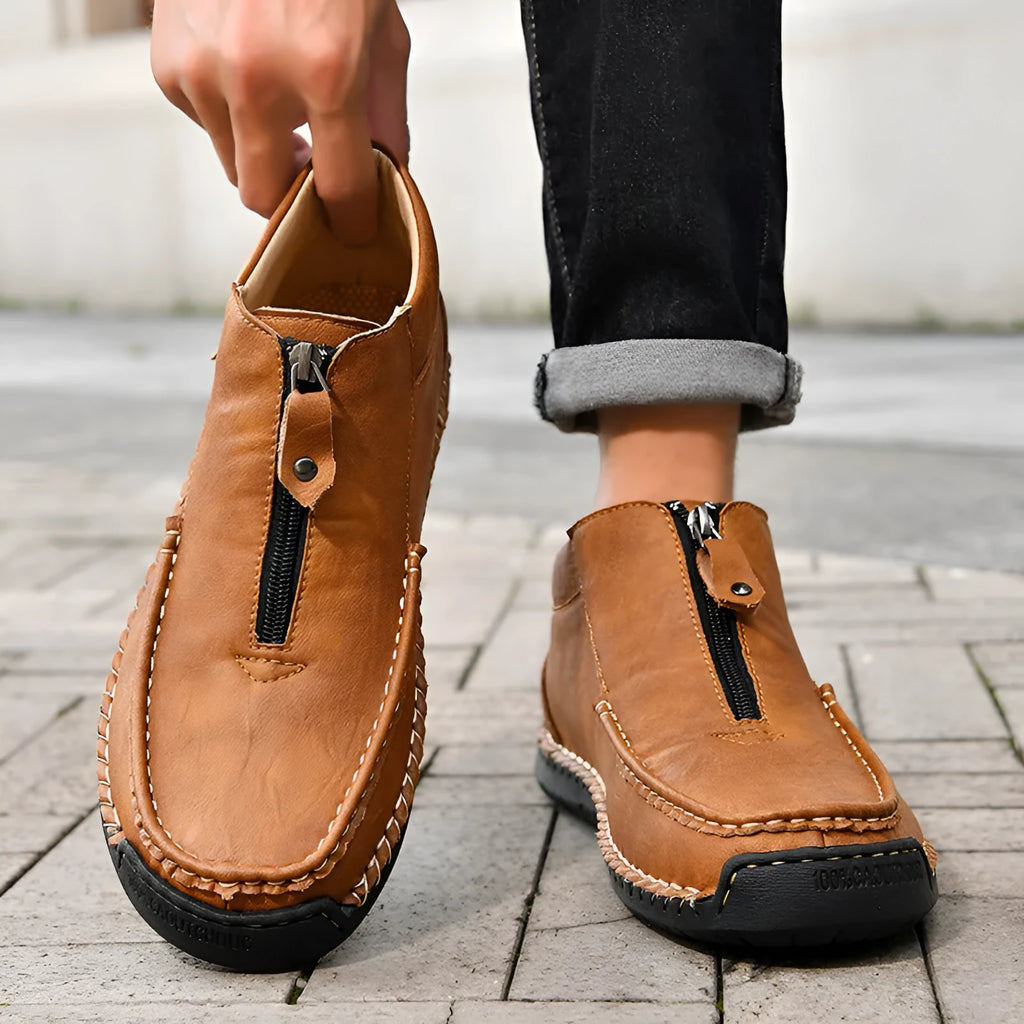 Men's black slip-on loafers with round toe and rubber sole on a plain background.