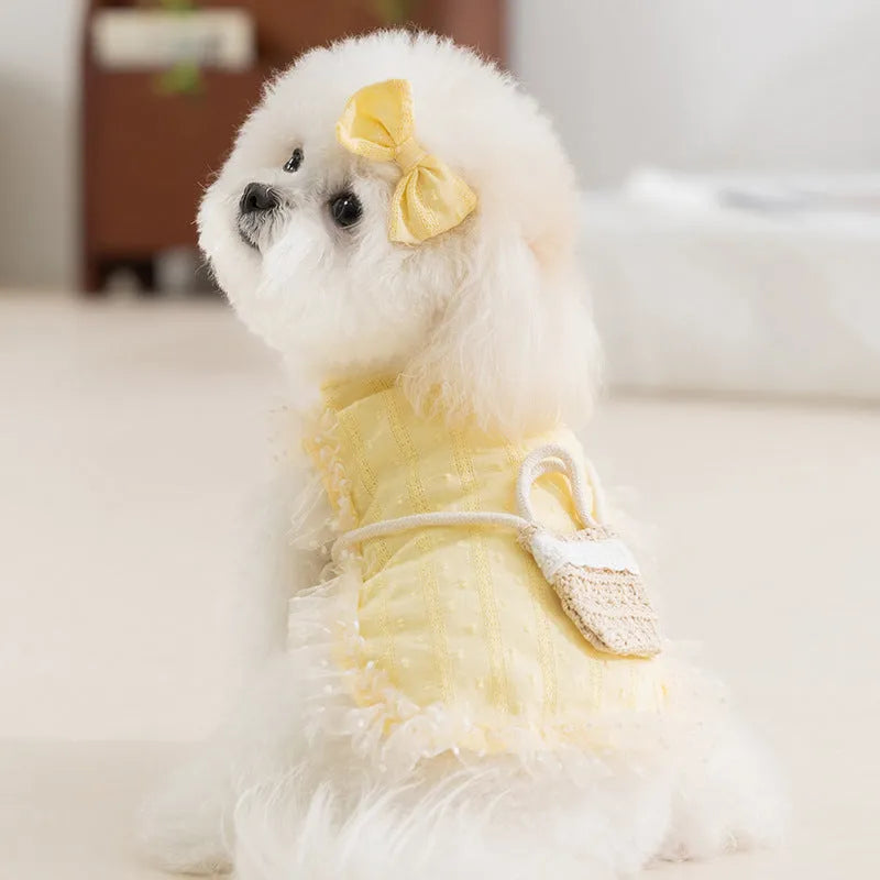 Two-tone blue sleeveless pet outfit with ruffles, matching bow, and small woven crossbody bag on a small dog