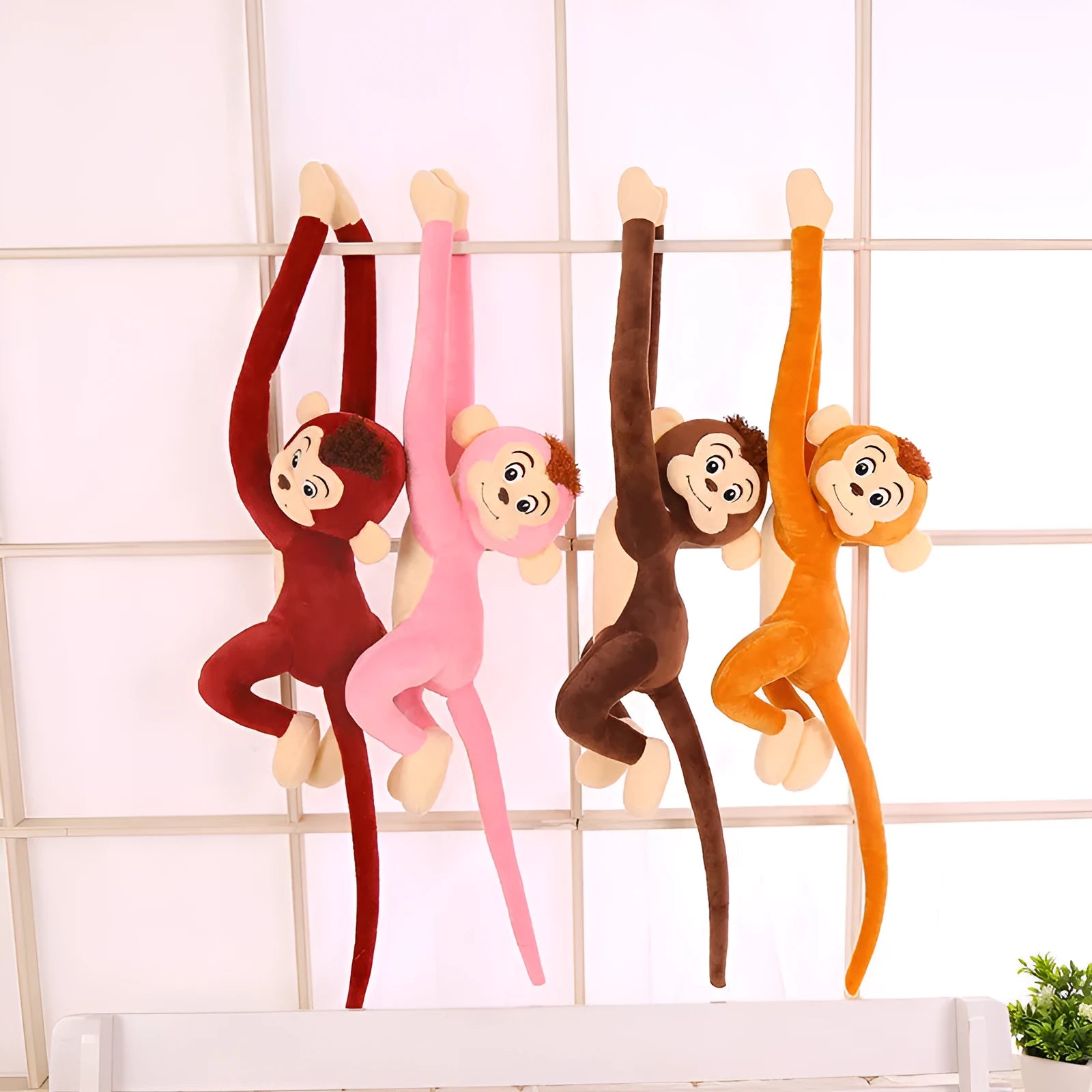 Long arm pink plush monkey toy hanging over a curtain rod as room decoration.