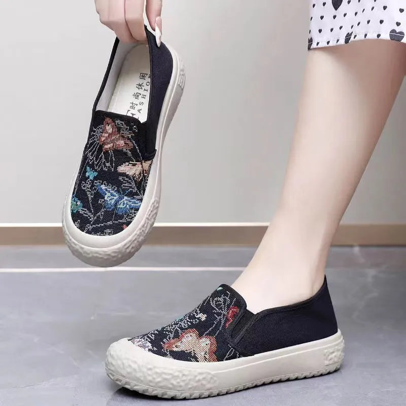 Women's black and white canvas slip-on shoes with round toe and decorative stitching.