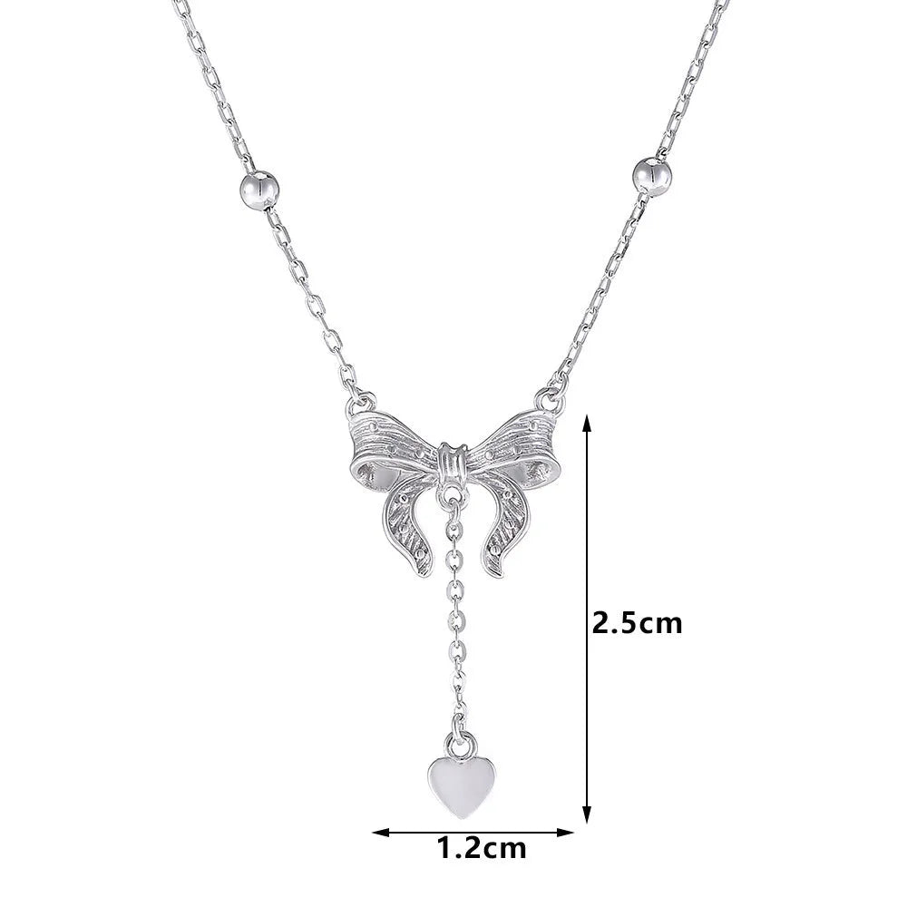 Silver necklace with heart-shaped pendant featuring bow detail on O-ring chain