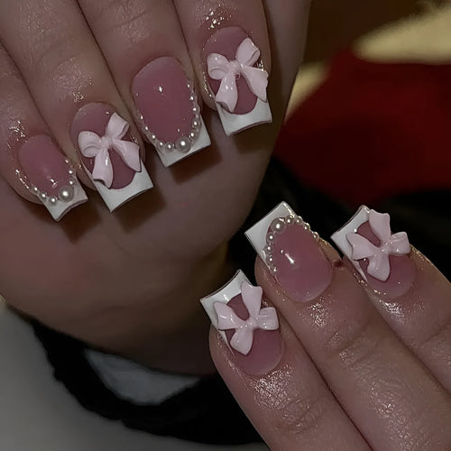 Short square French manicure artificial nails with white bow and floral patterns.