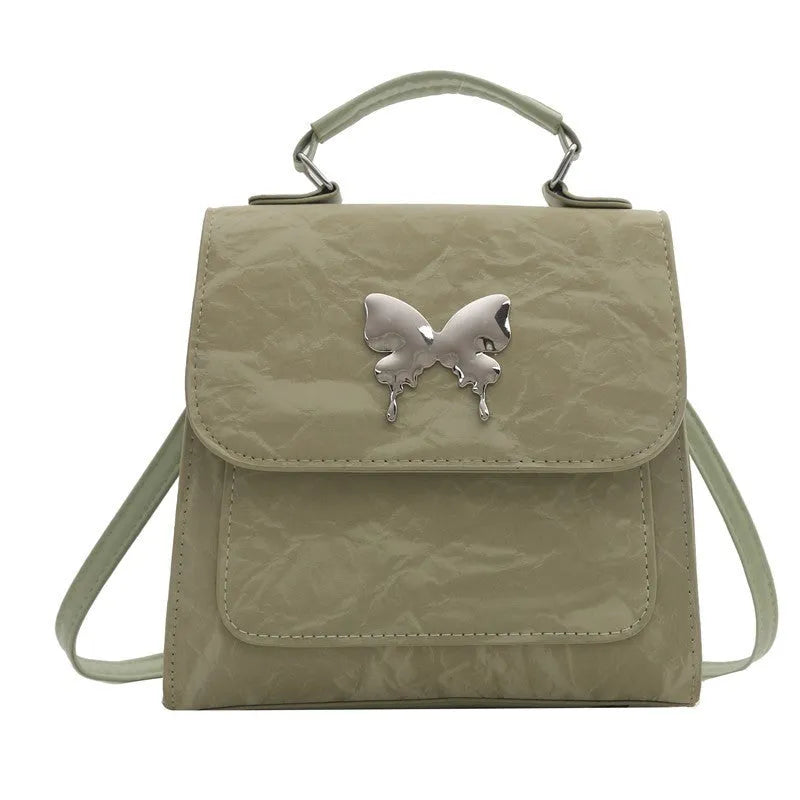 Preppy style white PU women's backpack with a black detachable bow decoration and visible stitching.