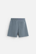 Man wearing a loose blue short sleeve top and matching shorts from a casual polyester co-ord set.