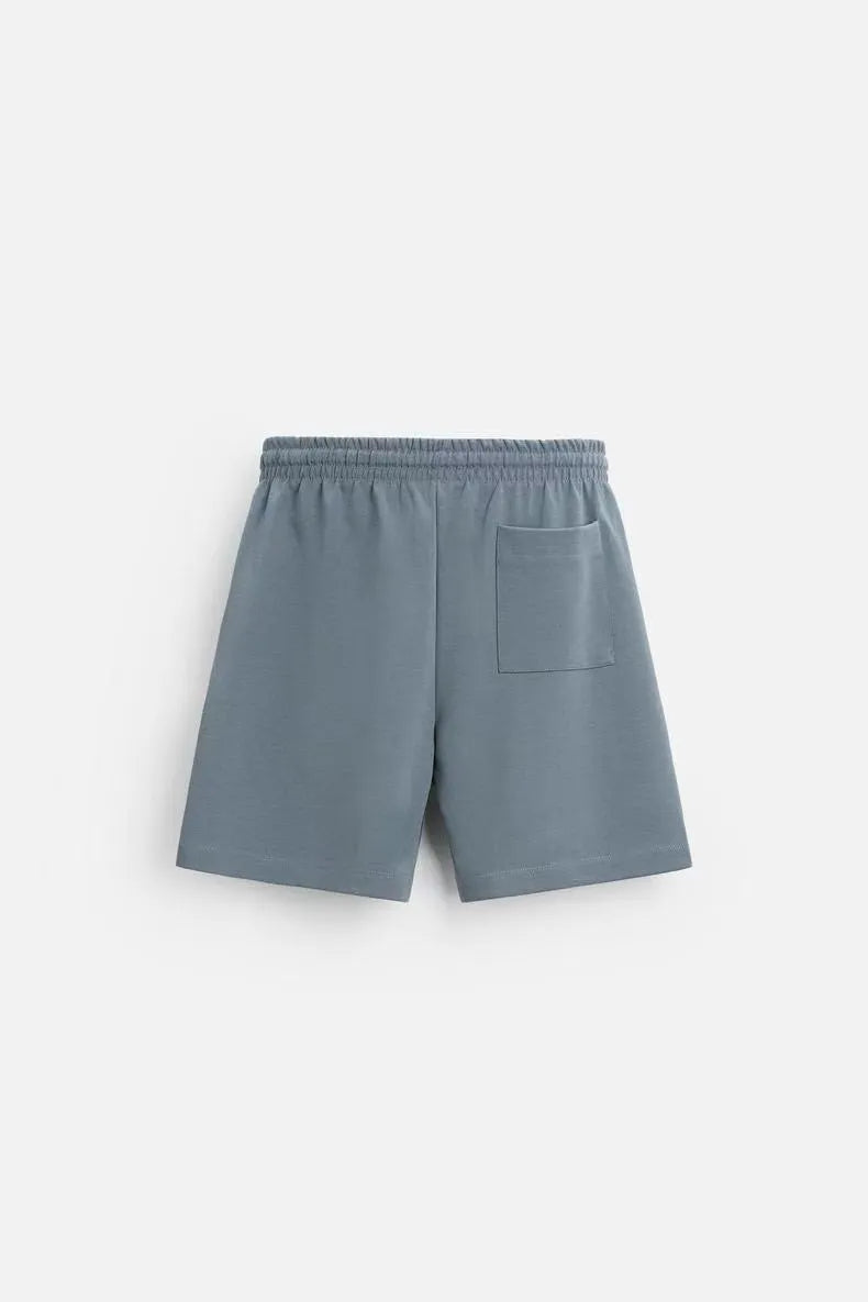 Man wearing a loose blue short sleeve top and matching shorts from a casual polyester co-ord set.