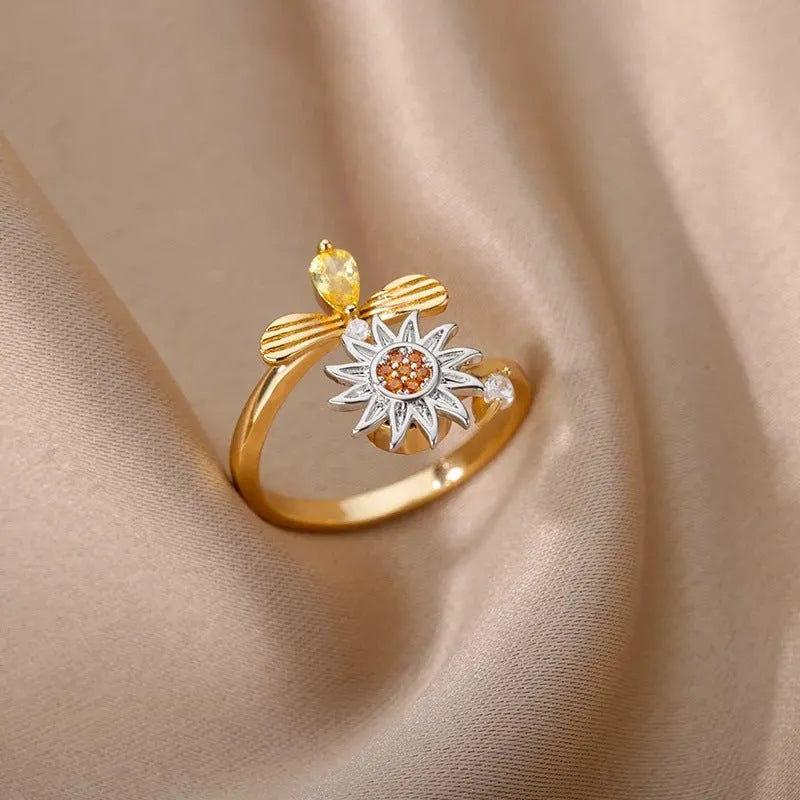 A geometric gold-coloured ring with an adjustable opening, shown rotating on a finger.