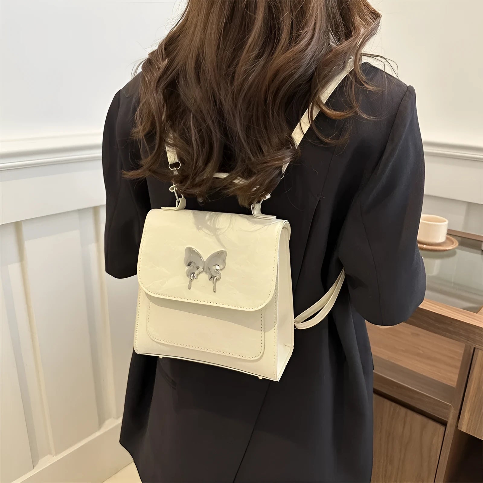 Preppy style white PU women's backpack with a black detachable bow decoration and visible stitching.
