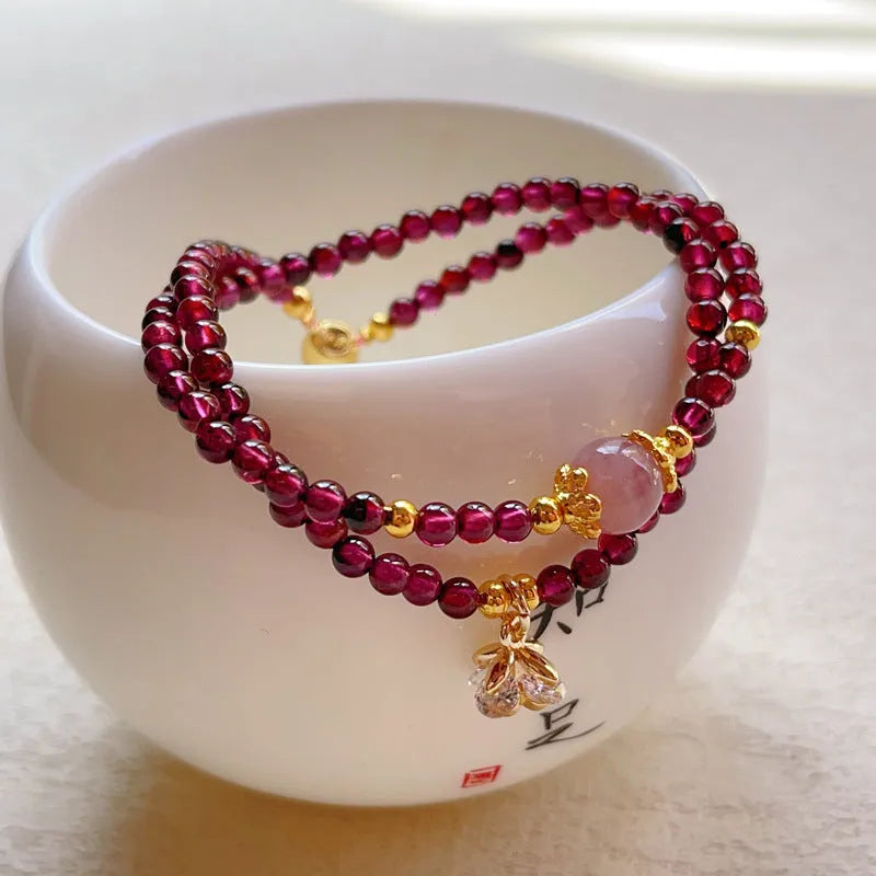 Close-up of a women's double ring bracelet made with natural garnet stones in H311 colour.