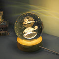 Transparent crystal ball night lamp with 3D carved jellyfish design, lit with soft blue glow on a round base.