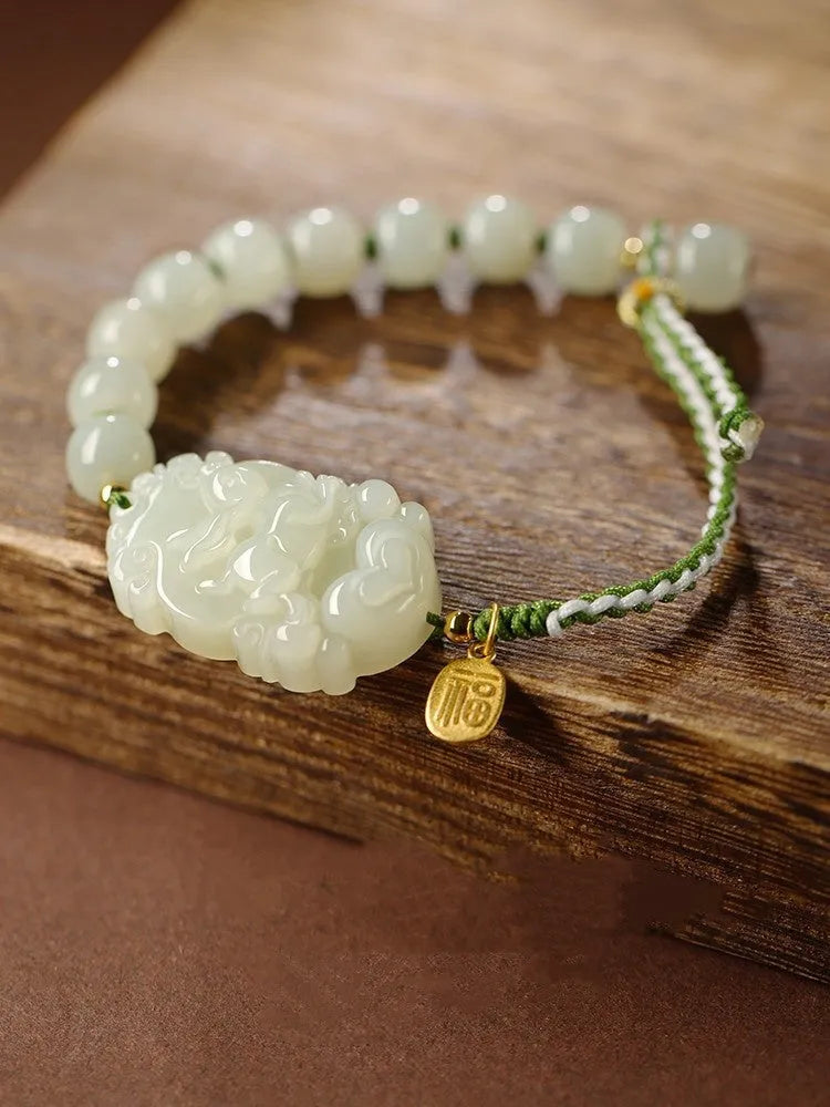 Red rope bracelet with a carved green Hetian jade Rabbit charm and a small S925 silver card on a cotton cord.