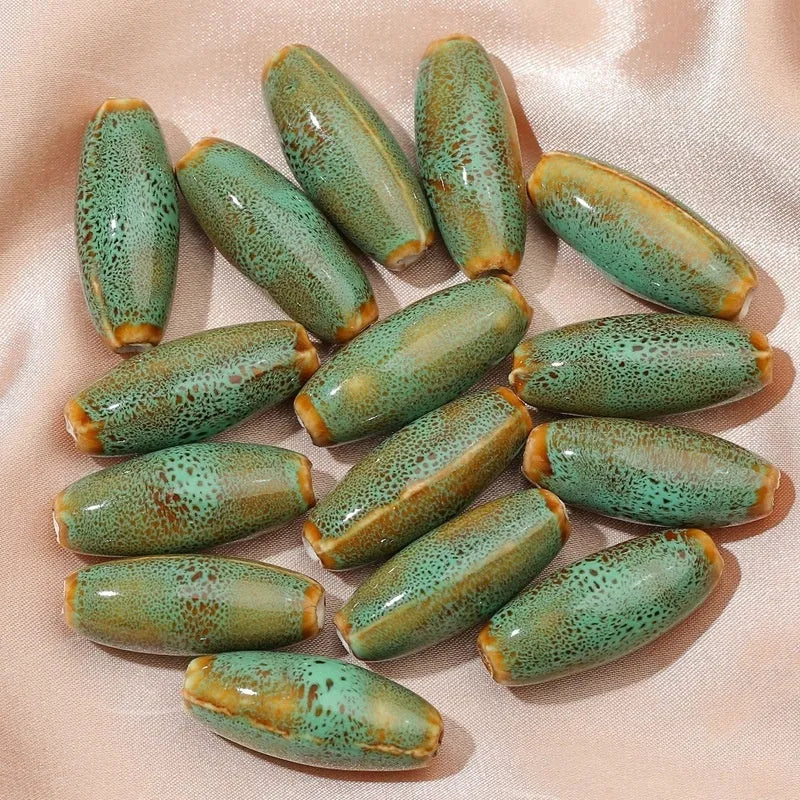 Assortment of ceramic bullet beads in pink, yellow, blue, red, coffee, green, orange, and mixed flower glaze colours.