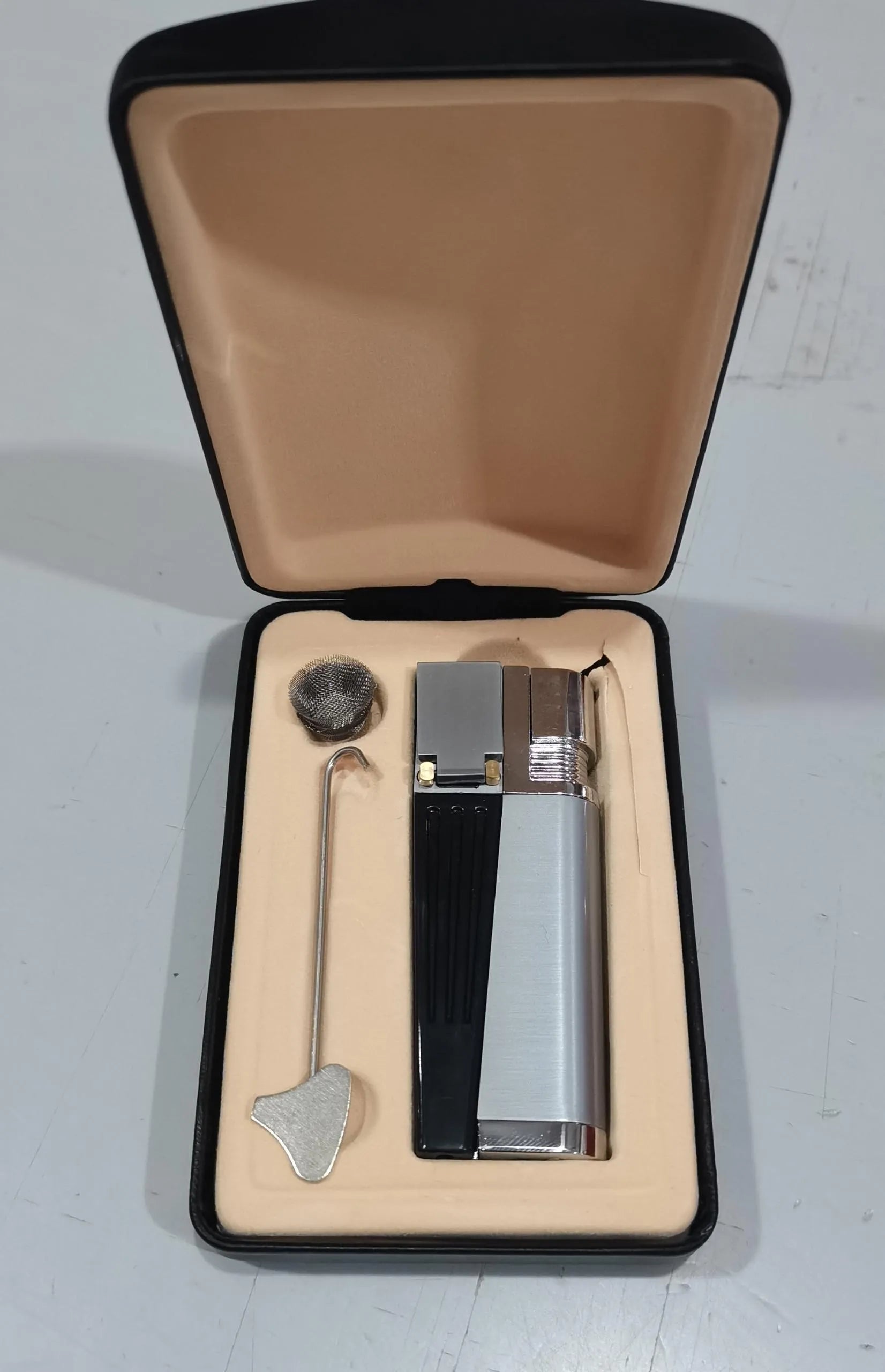 Silver foldable metal pipe lighter in open position showing flame mechanism and storage compartment.