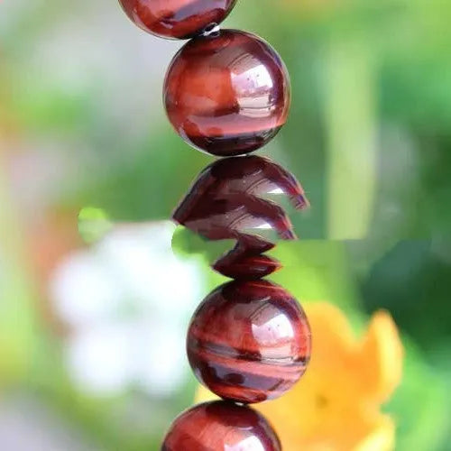 Geometric wood alexandrite bracelet with round beads showing Lightning Cat's Eye effect.