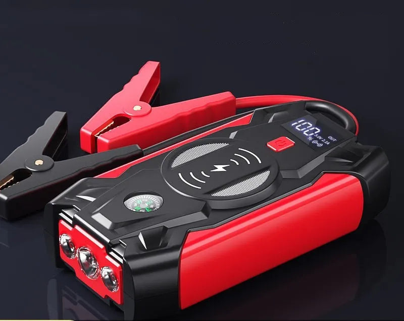 Red 12V car battery jump starter power pack with battery clips on a black background.