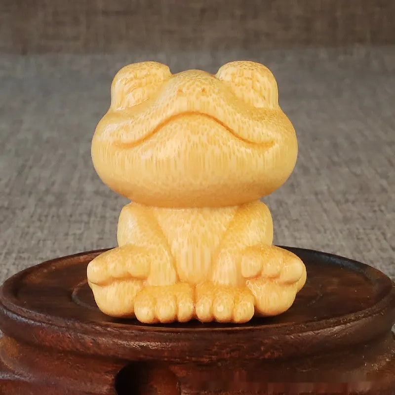 Solid bamboo carving of a smiling cartoon frog ornament, 5cm tall.
