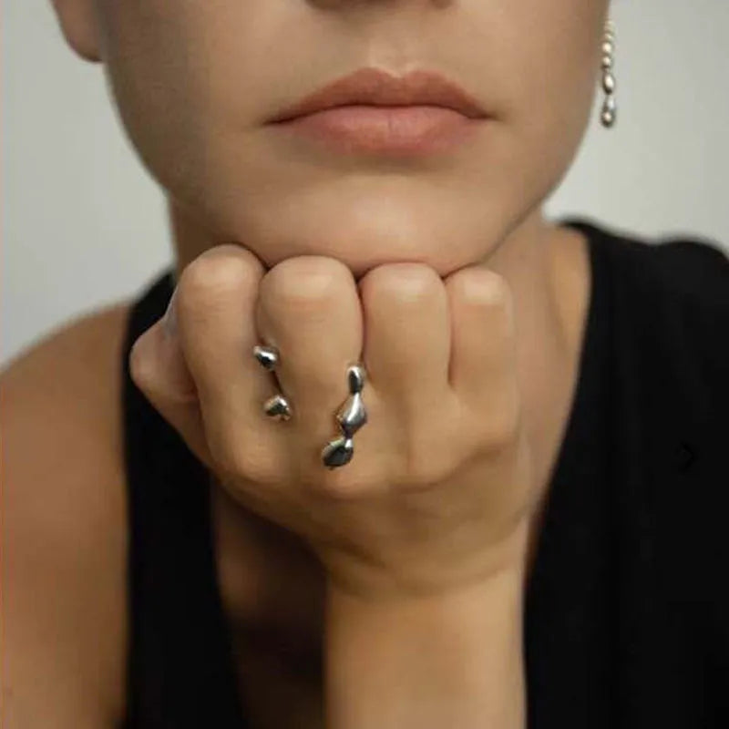 Gold tone brass ring with open circle design and central sphere on a person's finger.