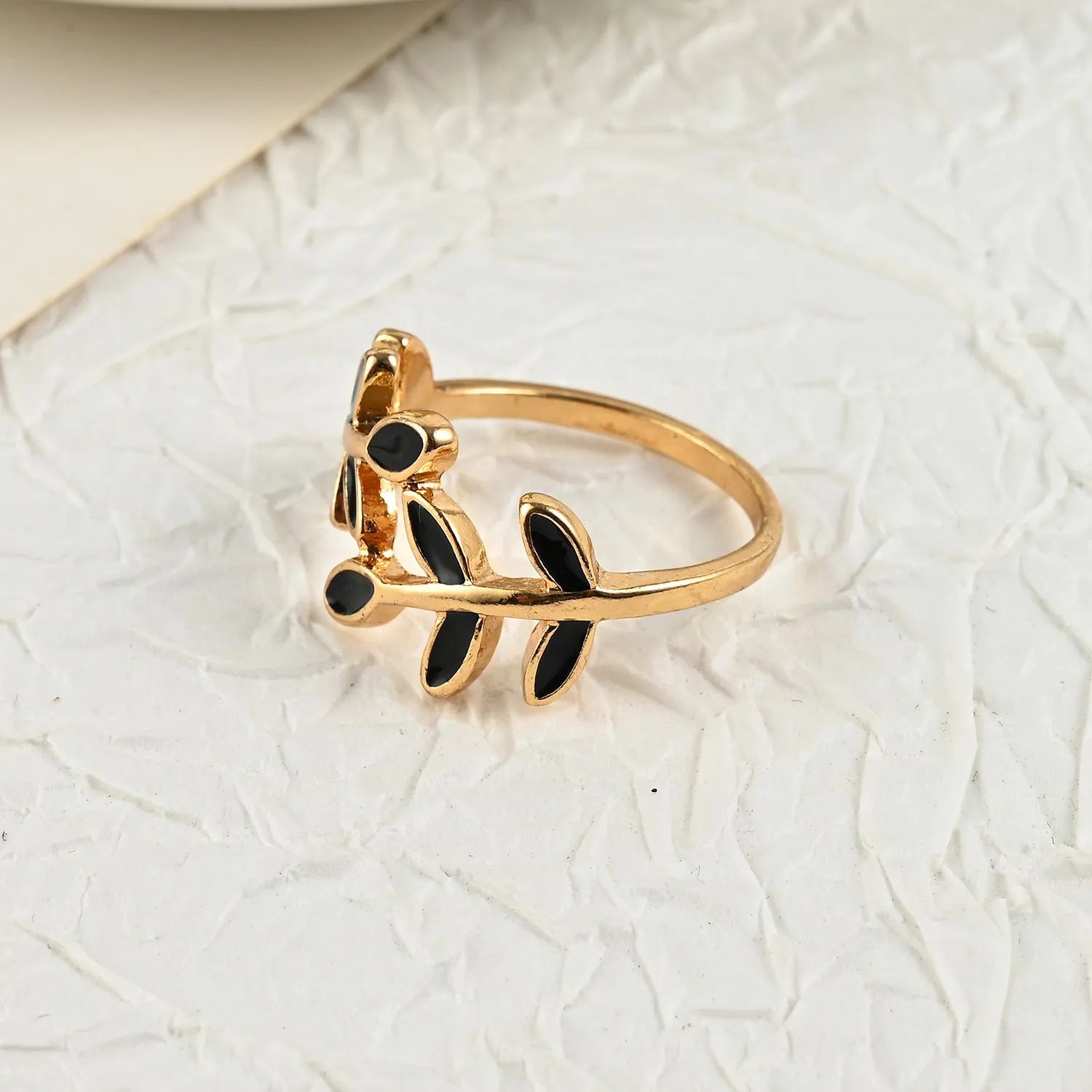 Gold electroplated acrylic ring with a geometric leaf and flower design on a model's index finger.