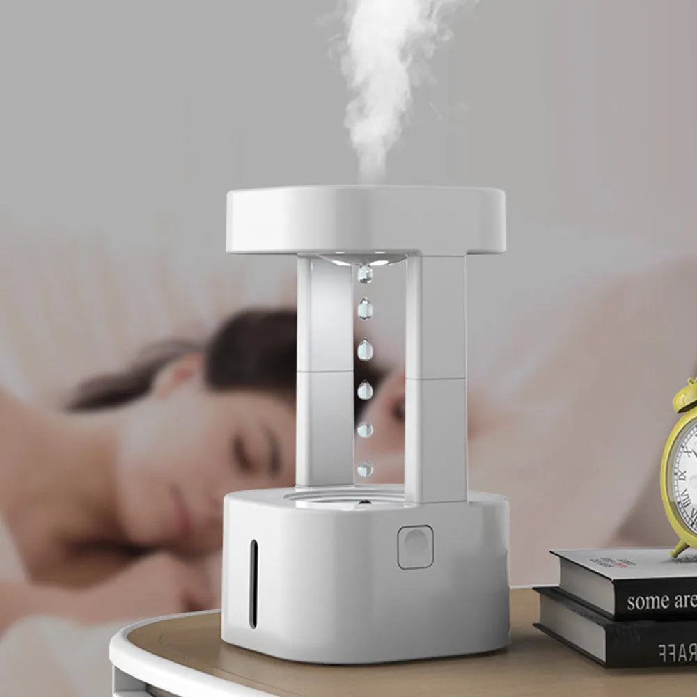 White anti-gravity water drop humidifier with coloured light on a desk next to USB cable